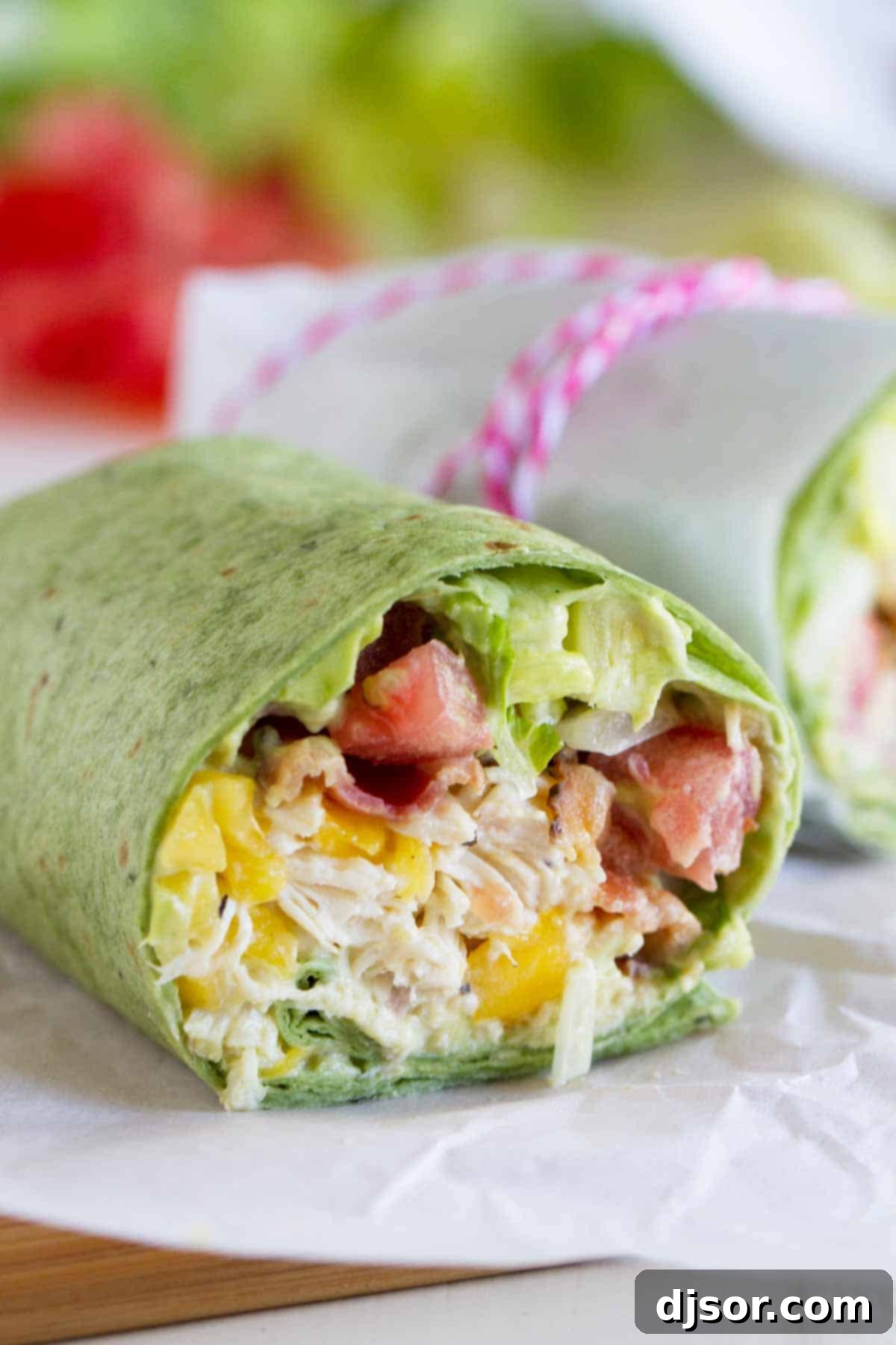 California Club Chicken Wrap with shredded chicken, avocado, mango, bacon, lettuce, and tomatoes, ready to be rolled.