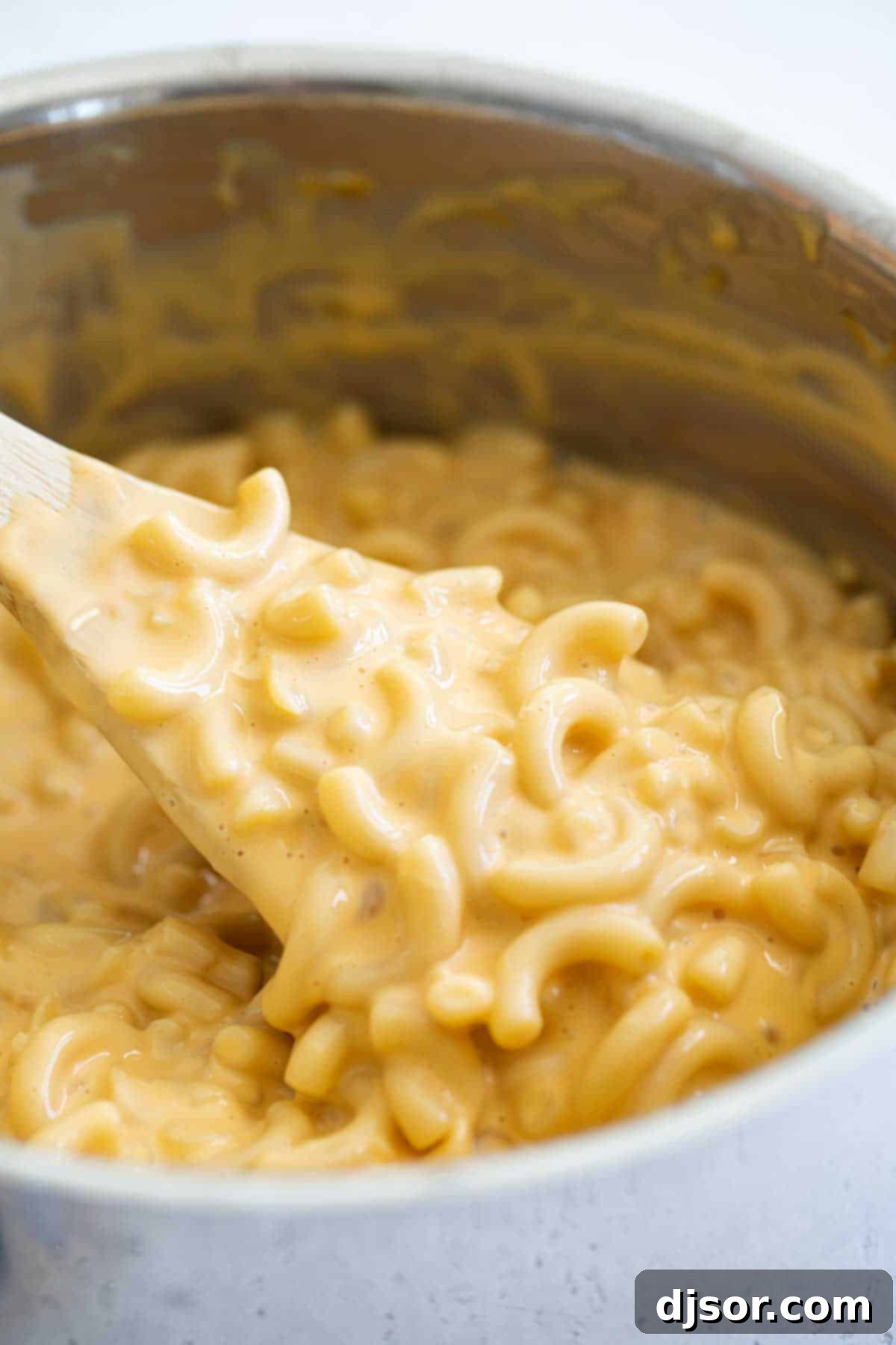 A close-up of a spoon lifting a generous portion of easy, homemade mac and cheese from a bowl, showcasing its rich and creamy texture.