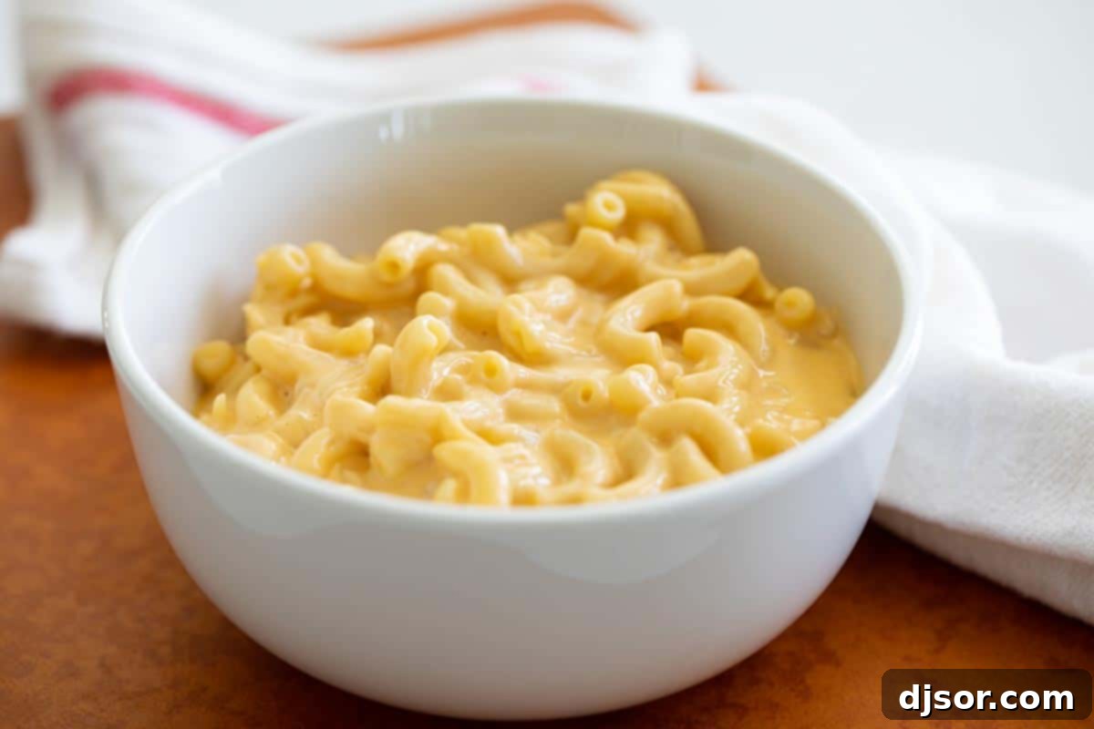 A beautifully presented bowl of creamy mac and cheese, garnished with a sprinkle of fresh herbs, emphasizing its rich texture and inviting appearance.