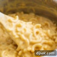 A close-up of a spoon lifting a generous portion of easy, homemade mac and cheese from a bowl, showcasing its rich and creamy texture.