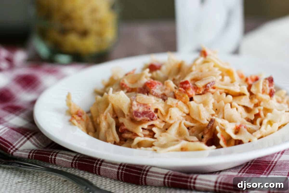 Smoky Tomato Bacon Pasta - A delectable blend of tomatoes, bacon, and cream cheese. A serving of Smoky Tomato Bacon Pasta on a white plate, garnished with fresh herbs.