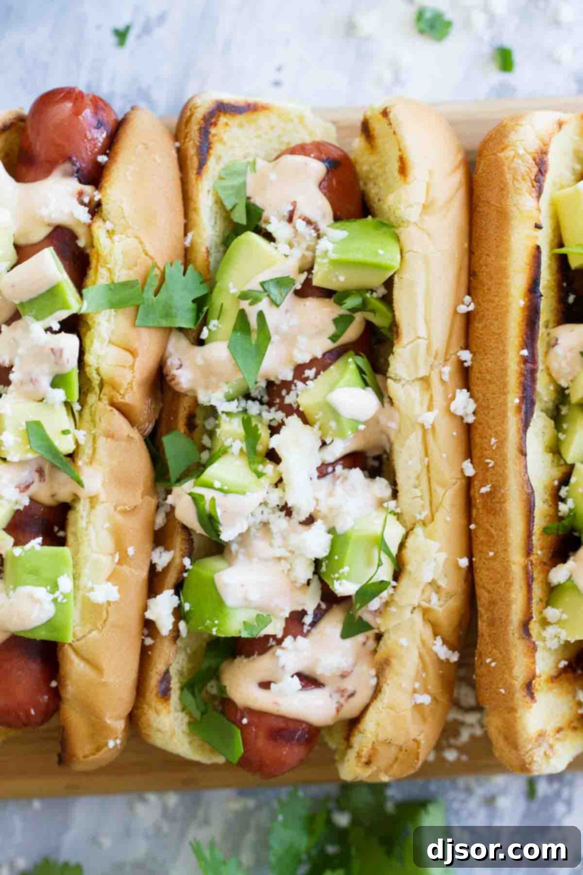 Hot dogs with Tex-Mex flair - this Mexican Hot Dog recipe gives you hot dogs topped with a chipotle mayonnaise, avocados, cheese and cilantro. Flavorful Mexican Hot Dogs topped with creamy avocado and crumbled cotija cheese, ready to be enjoyed.