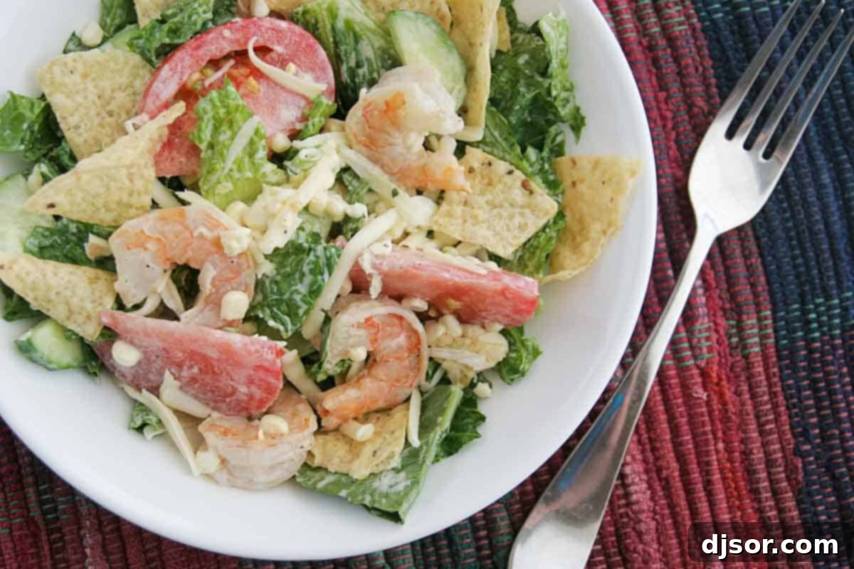 A vibrant Tex-Mex salad featuring plump shrimp, sweet corn, and crisp greens, dressed with ranch and garnished with cheese, served in a bowl