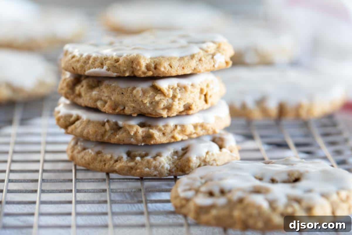 Four perfectly iced oatmeal cookies, stacked neatly, showcasing their soft texture and sweet glaze.