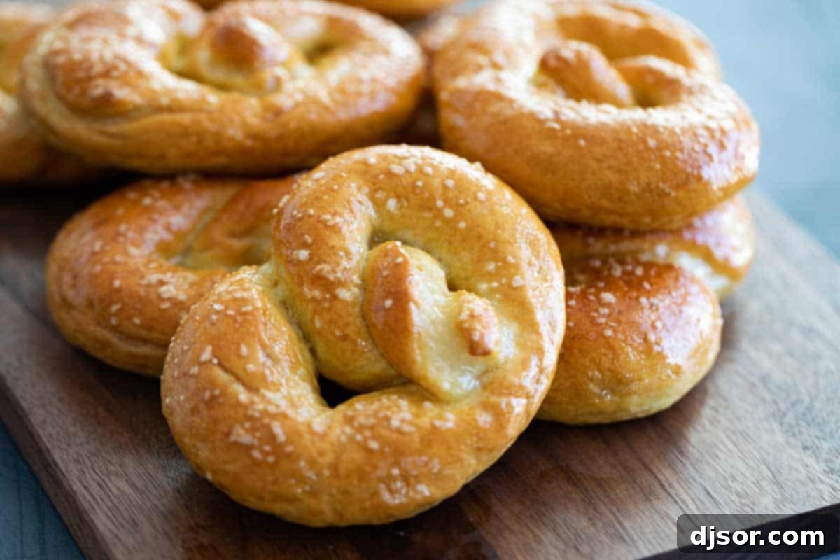 Homemade soft pretzel on a wooden board with a stack of golden brown pretzels behind