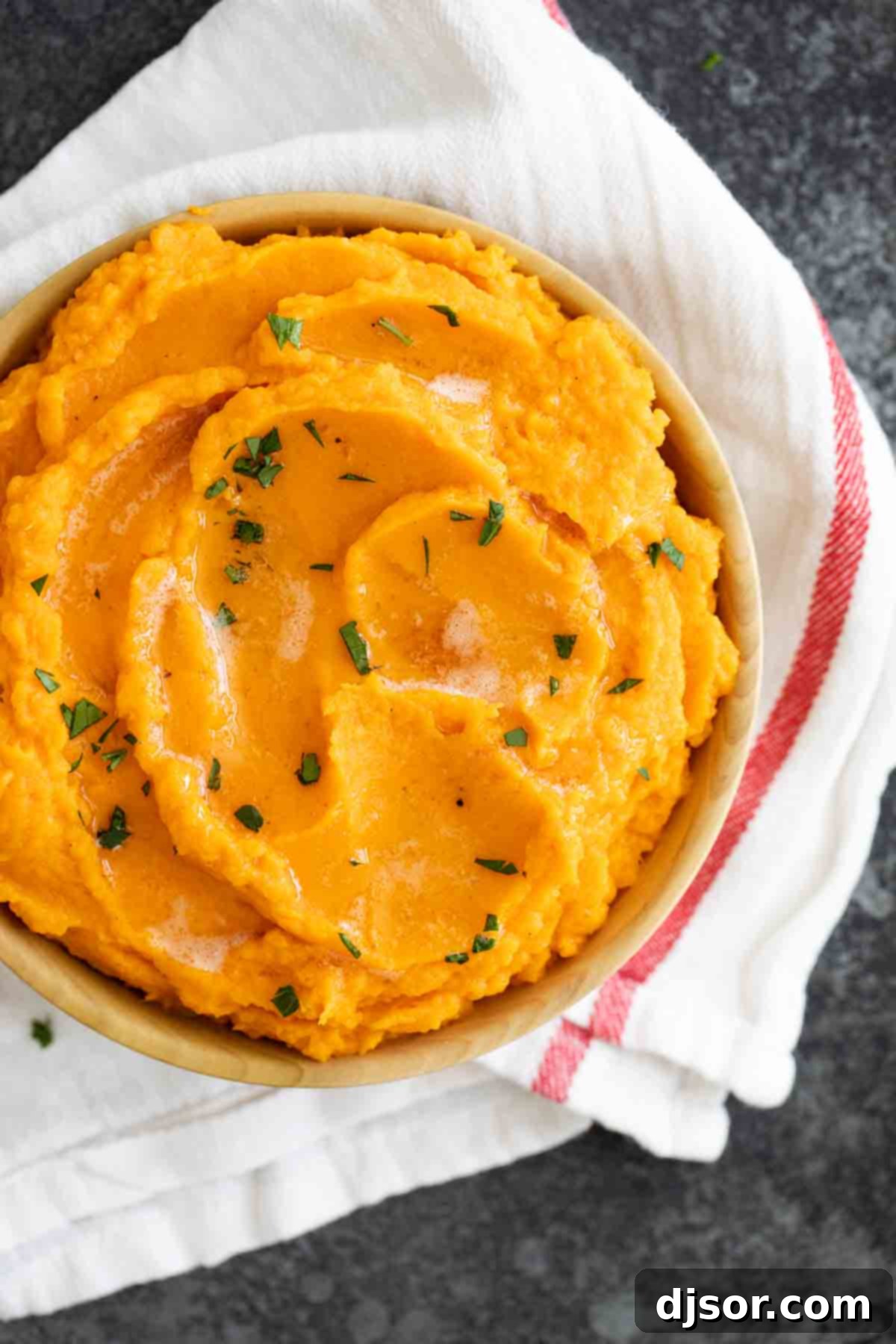 A vibrant and appetizing close-up of Mashed Sweet Potatoes with Brown Butter. Top-down view of a bowl of fluffy, golden mashed sweet potatoes, showcasing its smooth texture and inviting color.