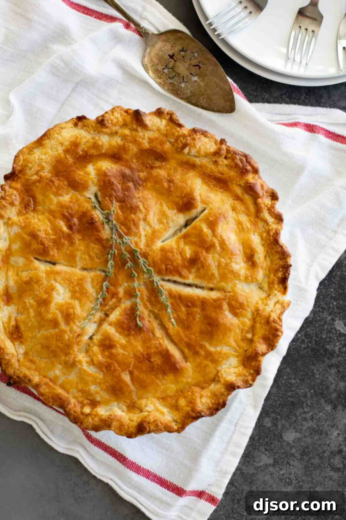 Whole Homemade Chicken Pot Pie with Golden Crust A complete, golden-brown homemade chicken pot pie resting on a rustic cloth, ready to be sliced.