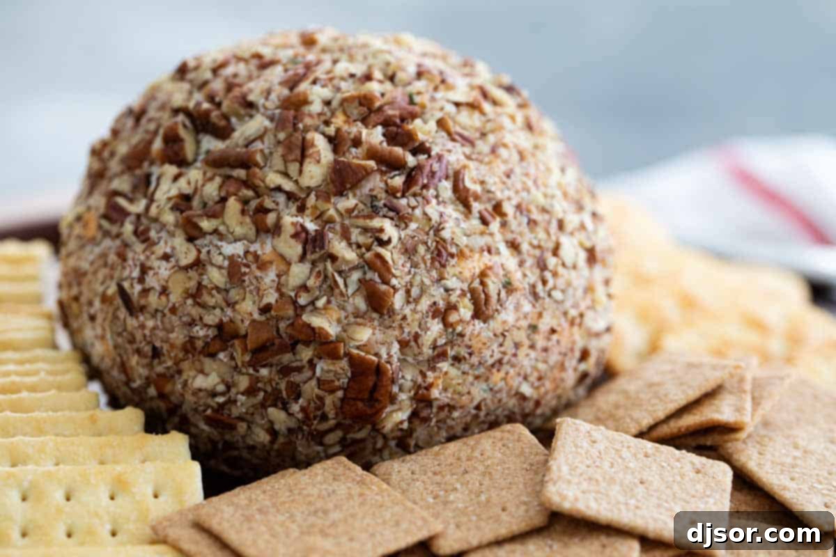 A classic appetizer that is perfect for a party, this Cheese Ball Recipe is the only one you’ll need! Filled with cheese and spices and coated in pecans, it is always a crowd favorite. Exquisitely crafted cheese ball, generously coated in chopped pecans, surrounded by a vibrant array of buttery crackers on a rustic wooden board, ready to be served at a festive gathering. This easy appetizer is perfect for parties.