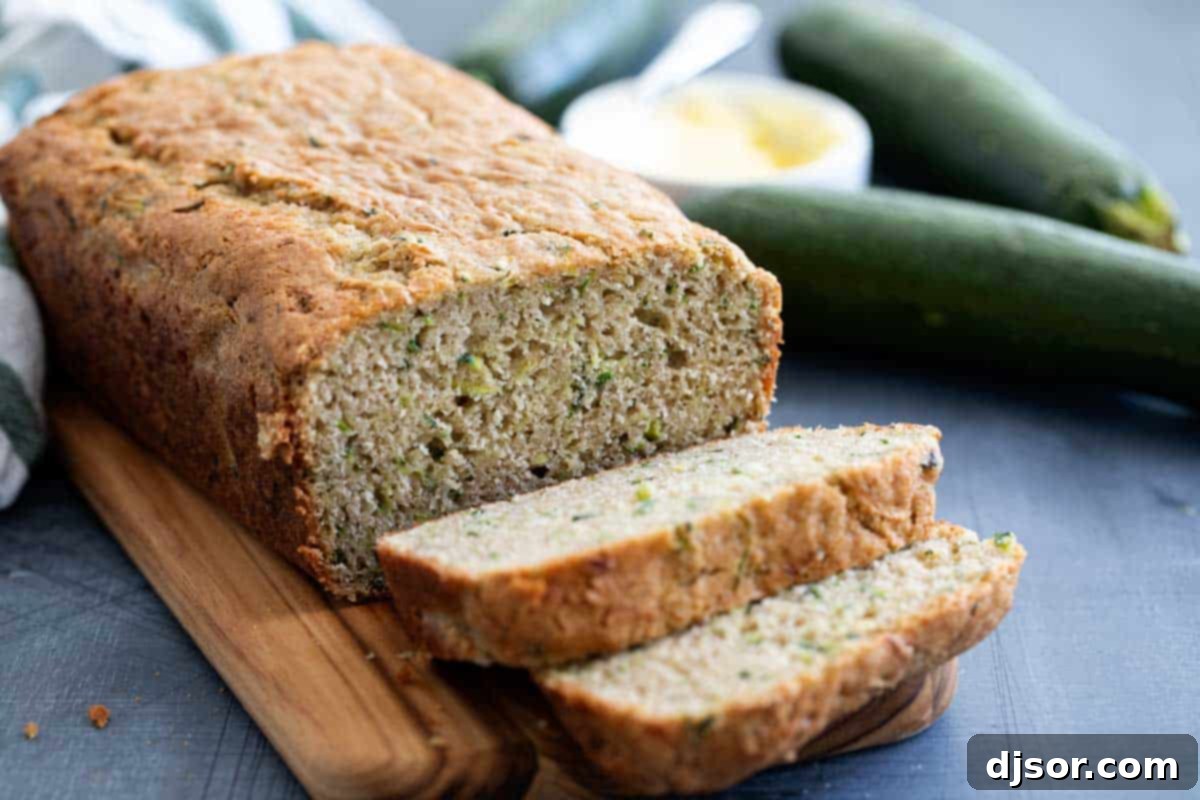 The best classic Zucchini Bread Recipe! A great way to use up that surplus of zucchini, this quick bread recipe is easy and perfectly spiced. Sliced moist classic zucchini bread on a wooden cutting board, ready to be enjoyed.