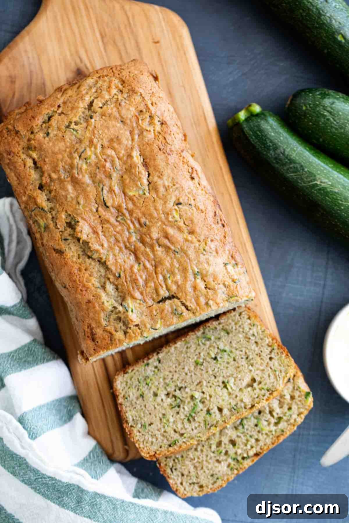 The best classic Zucchini Bread Recipe! A great way to use up that surplus of zucchini, this quick bread recipe is easy and perfectly spiced. Overhead view of a delicious zucchini bread loaf with two slices cut, showing its moist interior.