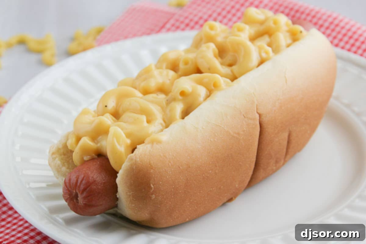Mac and Cheese Hot Dogs topped with homemade macaroni and cheese, glistening with creamy sauce.