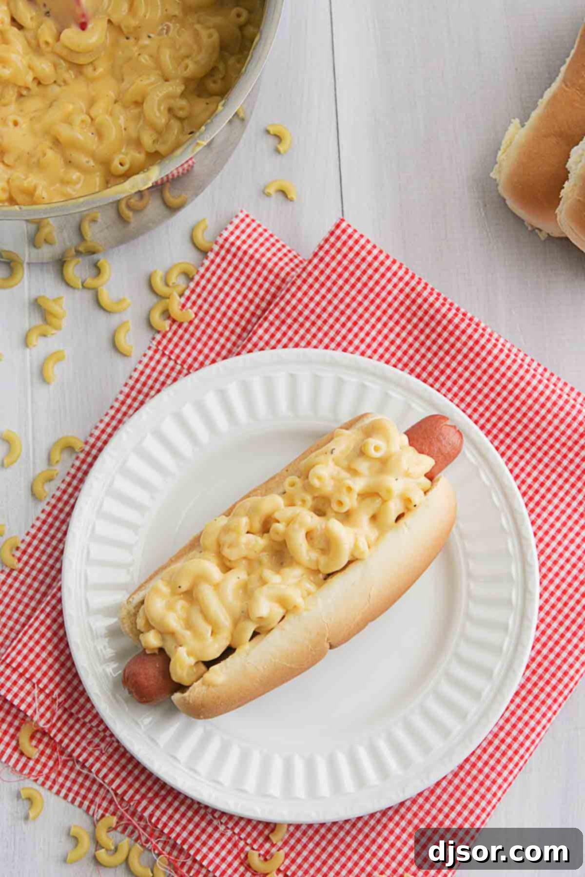 Close-up of three Mac and Cheese Hot Dogs, generously topped with creamy homemade mac and cheese and a sprinkle of fresh chives.