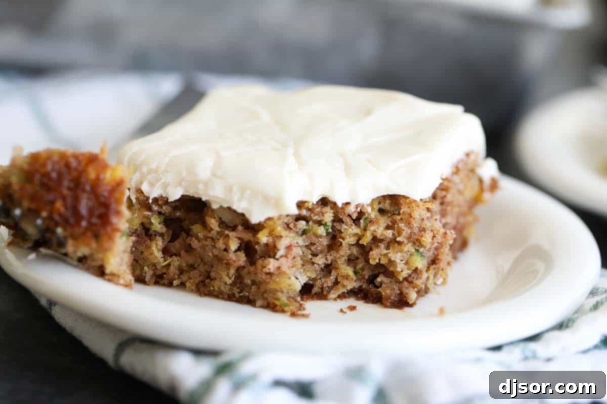 A close-up shot of a slice of Zucchini Cake with a bite taken, showcasing its moist texture and rich frosting.