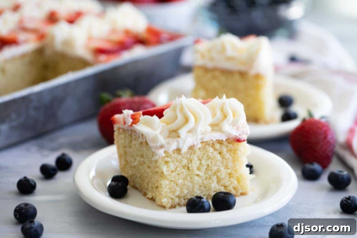 A slice of American Flag Cake on a white plate, showcasing the layers of cake, buttercream, and fruit.