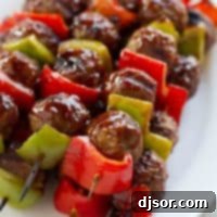 Tangy Glazed Meatball Skewers 2 Sweet and Sour Meatball Skewers stacked on a plate