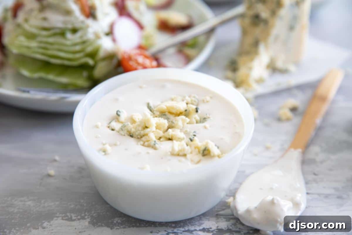 Tangy and creamy, this blue cheese dressing is better than bottled! Use it on a salad, serve it to dip with wings, or as a vegetable dipper. bowl of homemade blue cheese dressing with a salad in the background