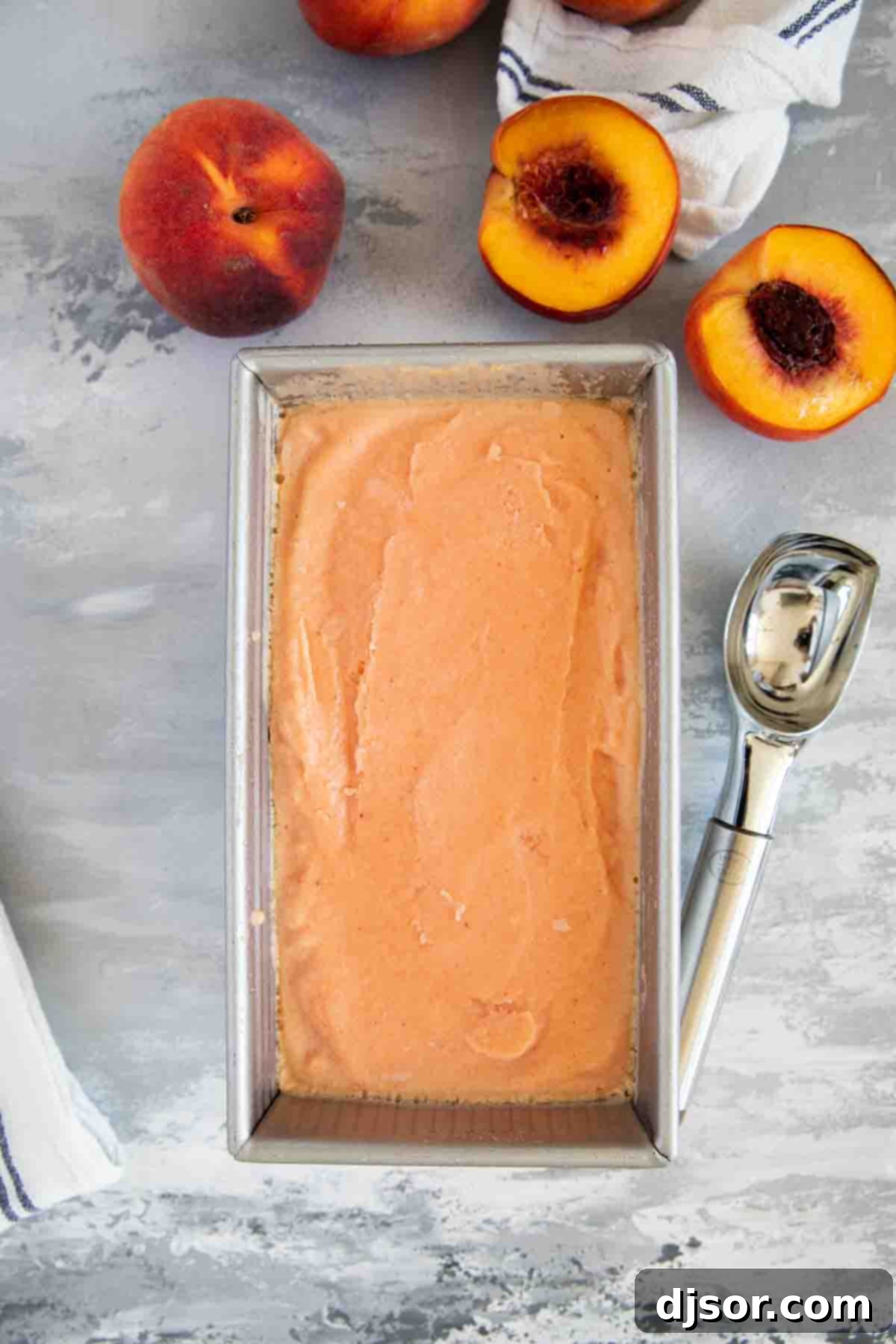 Sun-Kissed Peach Freeze 8 peach frozen yogurt in a stainless steel pan with fresh peaches