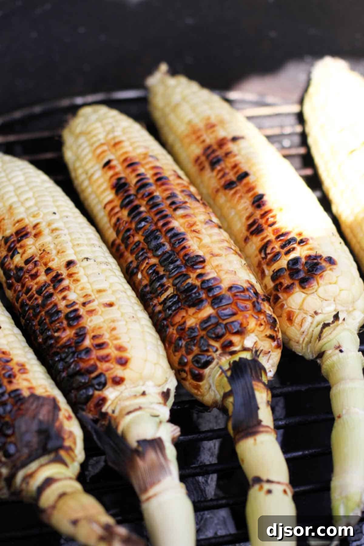 Grilling Corn for Quesadillas Corn grilling on a charcoal grill, showing smoky charring on the kernels