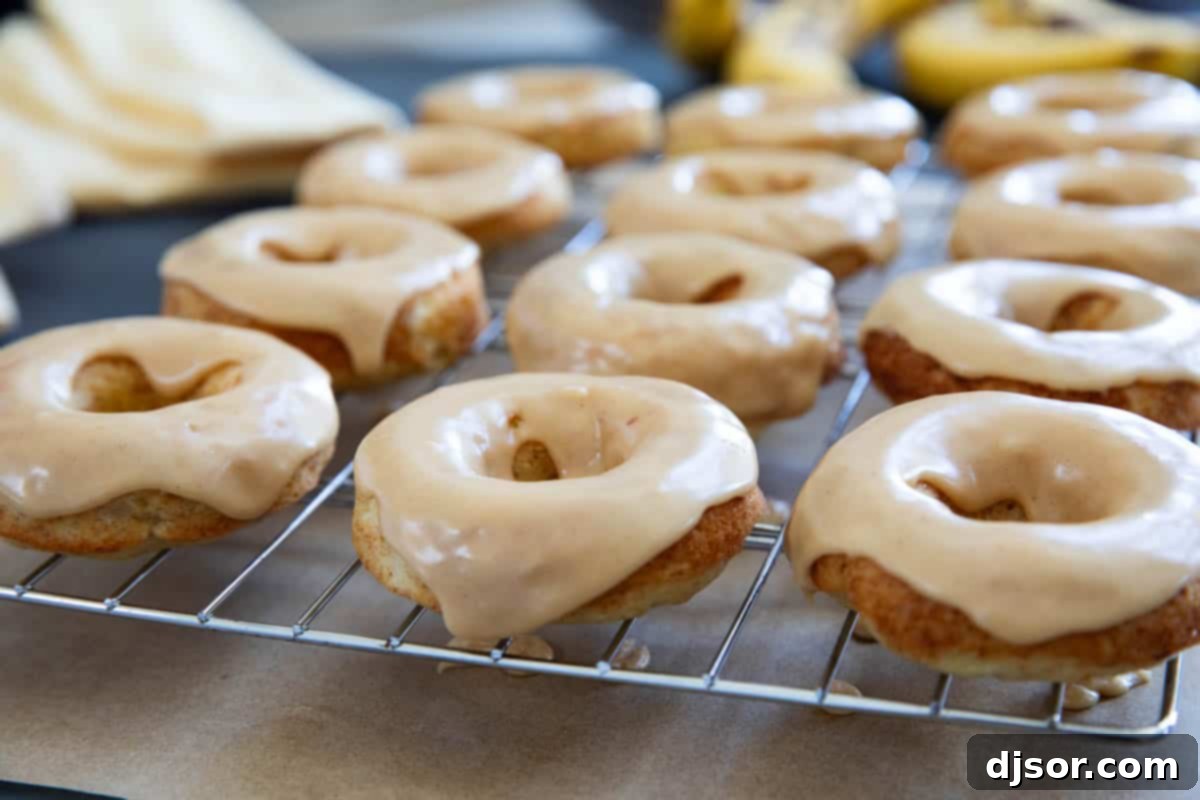 Banana donuts frosted with peanut butter icing cooling on a cooling rack.