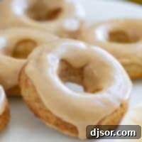 Baked banana donuts on a white plate, frosted with peanut butter icing.