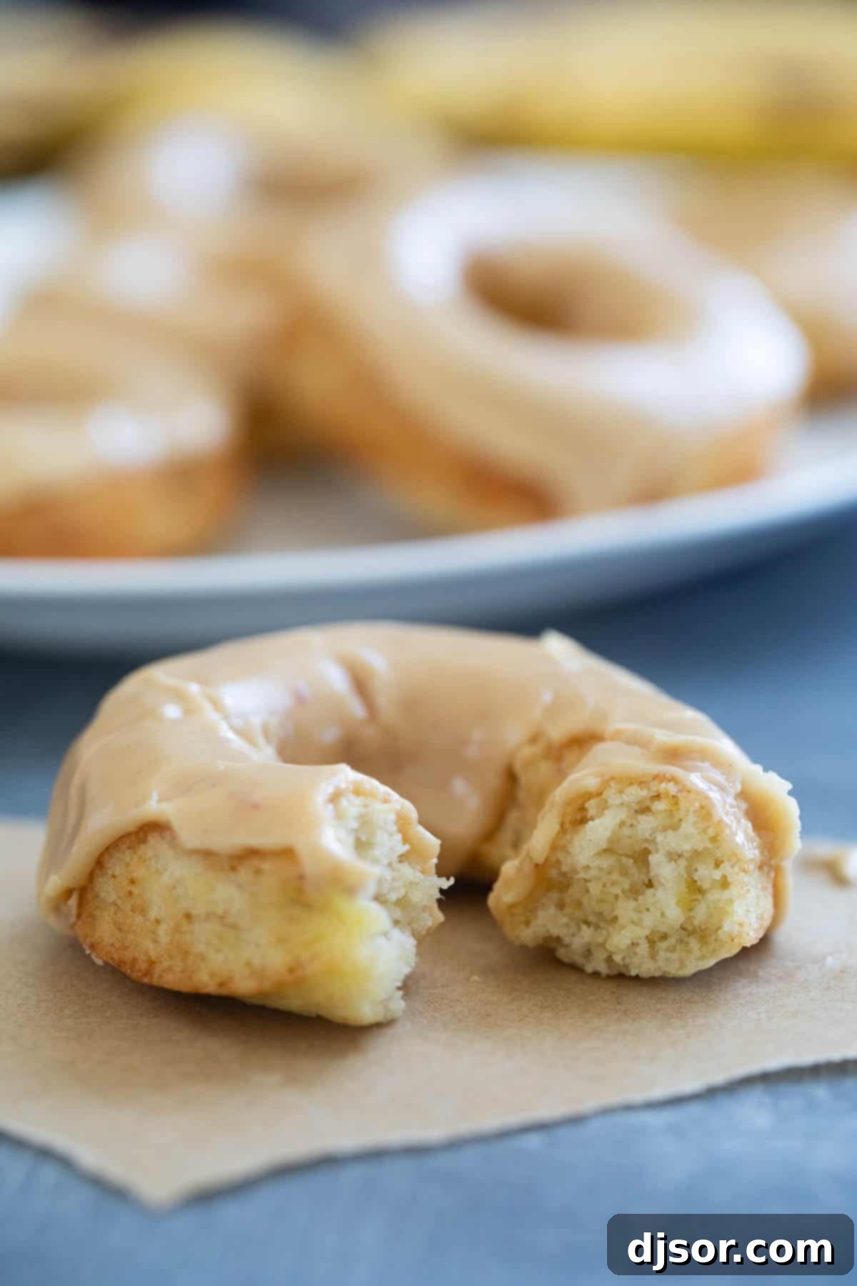 Baked banana donut with peanut butter icing with a bite taken from it.