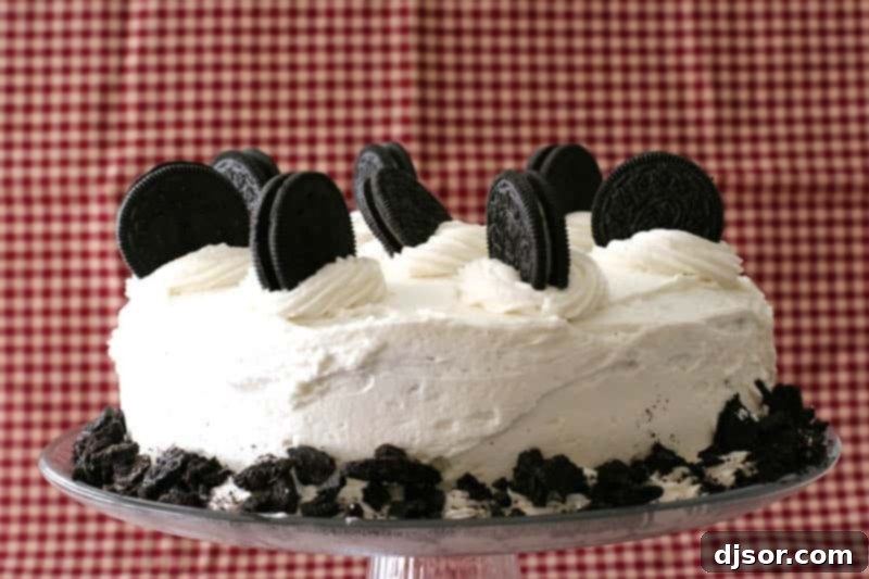 Rich Cookies and Cream Cake adorned with whole Oreo cookies and a creamy vanilla buttercream, set against a vibrant red background.