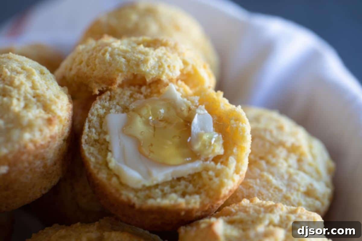Serving Suggestion: Corn Muffin with Butter and Honey A freshly baked corn muffin cut in half, revealing its moist interior, topped with melting butter and a drizzle of golden honey.