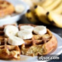 Irresistible Banana Waffle A close-up of a banana waffle with a bite taken out, showing the light and airy texture, topped with fresh banana slices and a hint of powdered sugar, making it look incredibly appetizing.