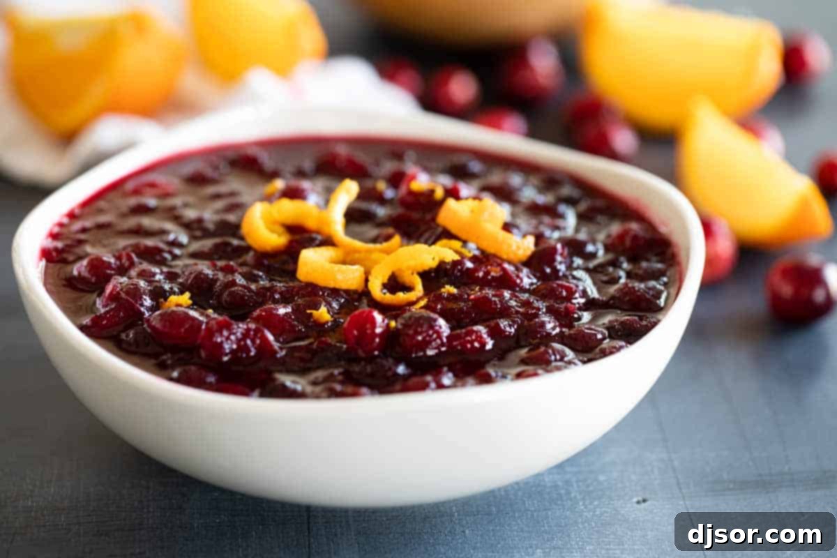 A beautiful bowl of homemade cranberry sauce, garnished with fresh orange zest, ready to be served at a holiday dinner.