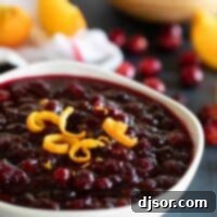 A vibrant bowl of homemade cranberry sauce, garnished with fresh orange zest, ready to be served.