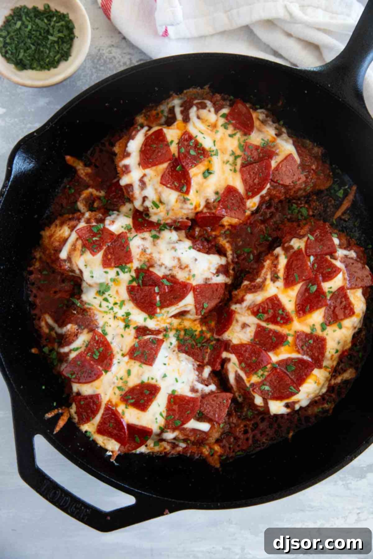 The finished Chicken Pepperoni in a cast iron skillet, bubbling with melted cheese and sauce, garnished with fresh parsley.