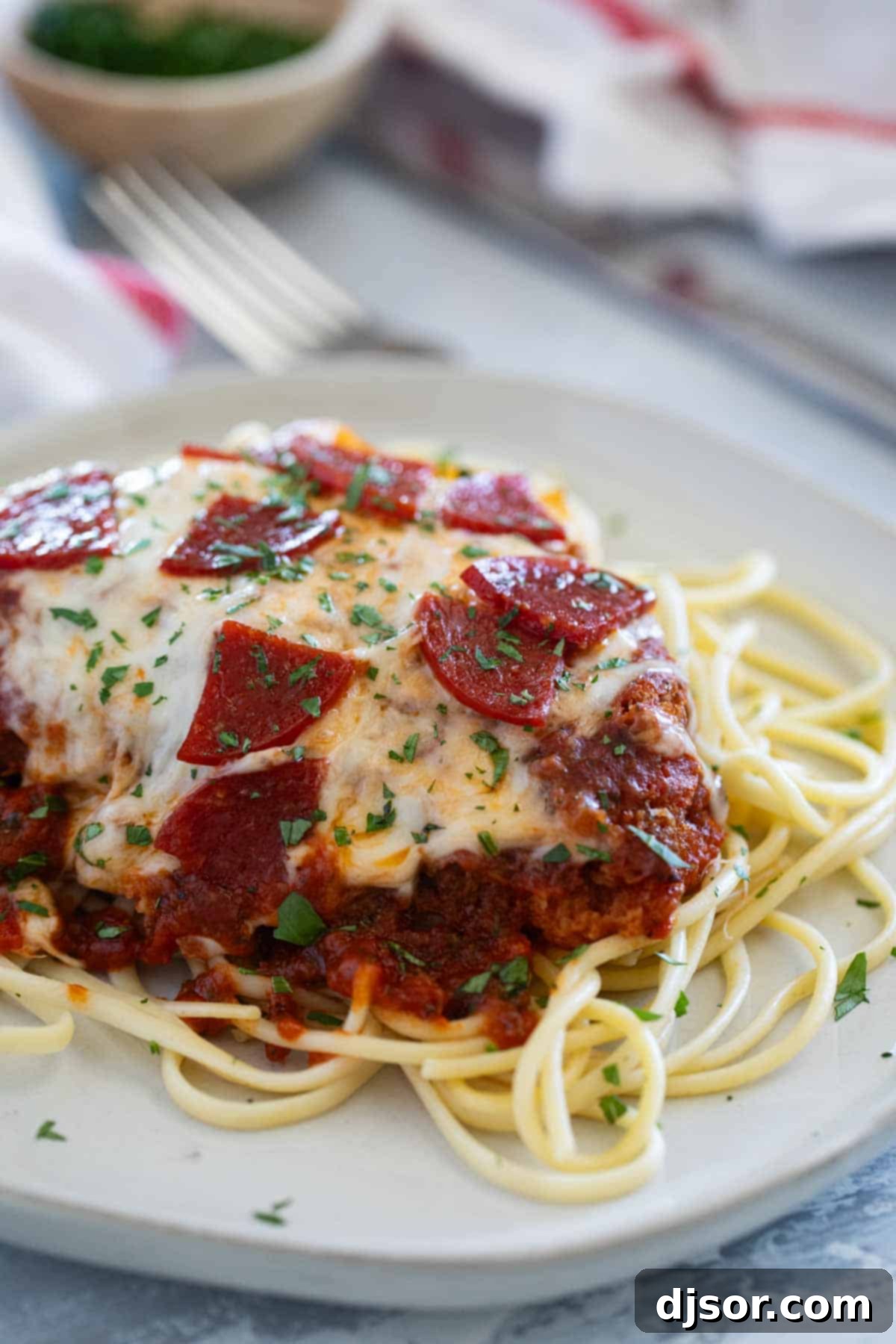 A delicious Chicken Pepperoni cutlet, a fusion of chicken parmesan and pepperoni pizza, garnished with fresh parsley.