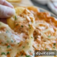 BBQ Chicken Dip on a round cracker with cheese coming off of it.