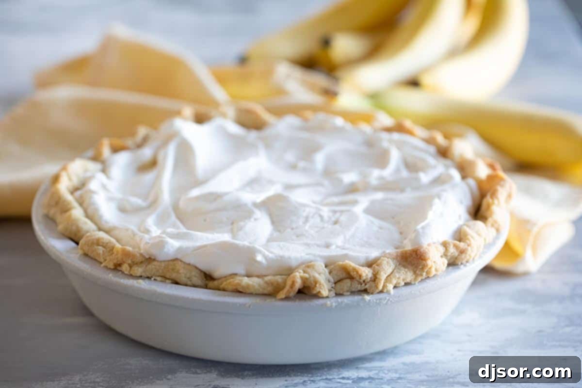 A beautiful, whole Banana Cream Pie topped with generous swirls of homemade whipped cream.