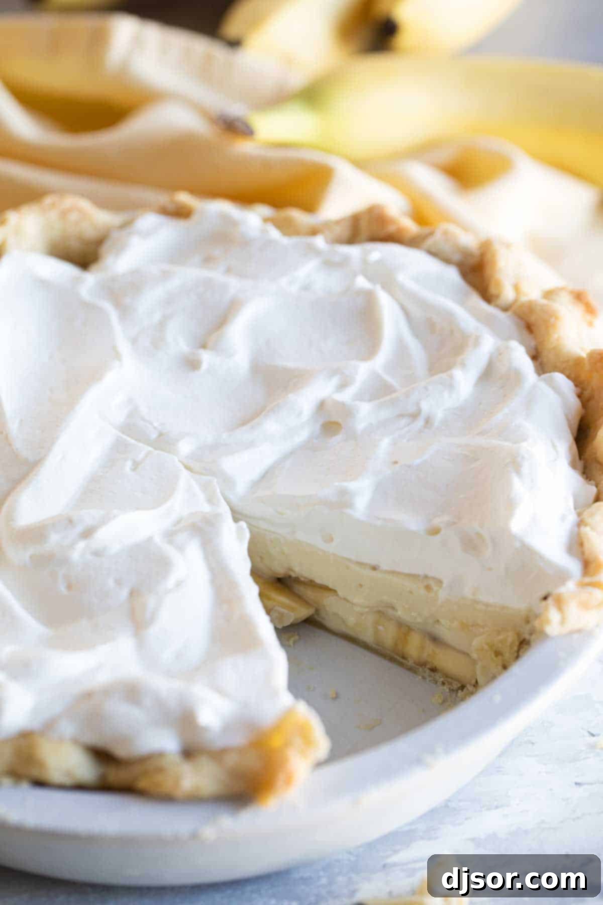 A freshly made Banana Cream Pie with a slice removed, revealing the delicious layers of banana and creamy filling.