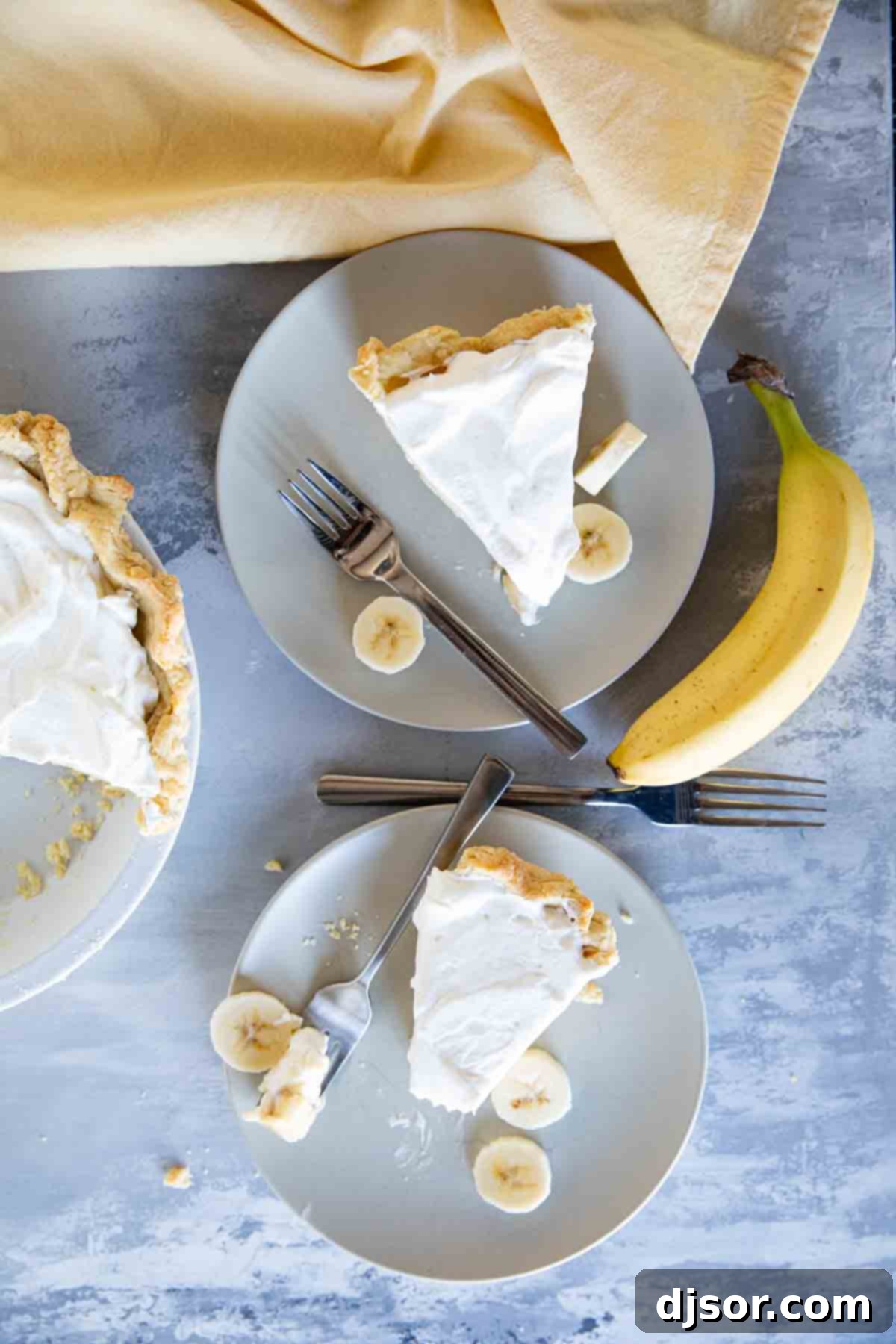 Two slices of Banana Cream Pie served on individual plates, garnished with extra whipped cream.