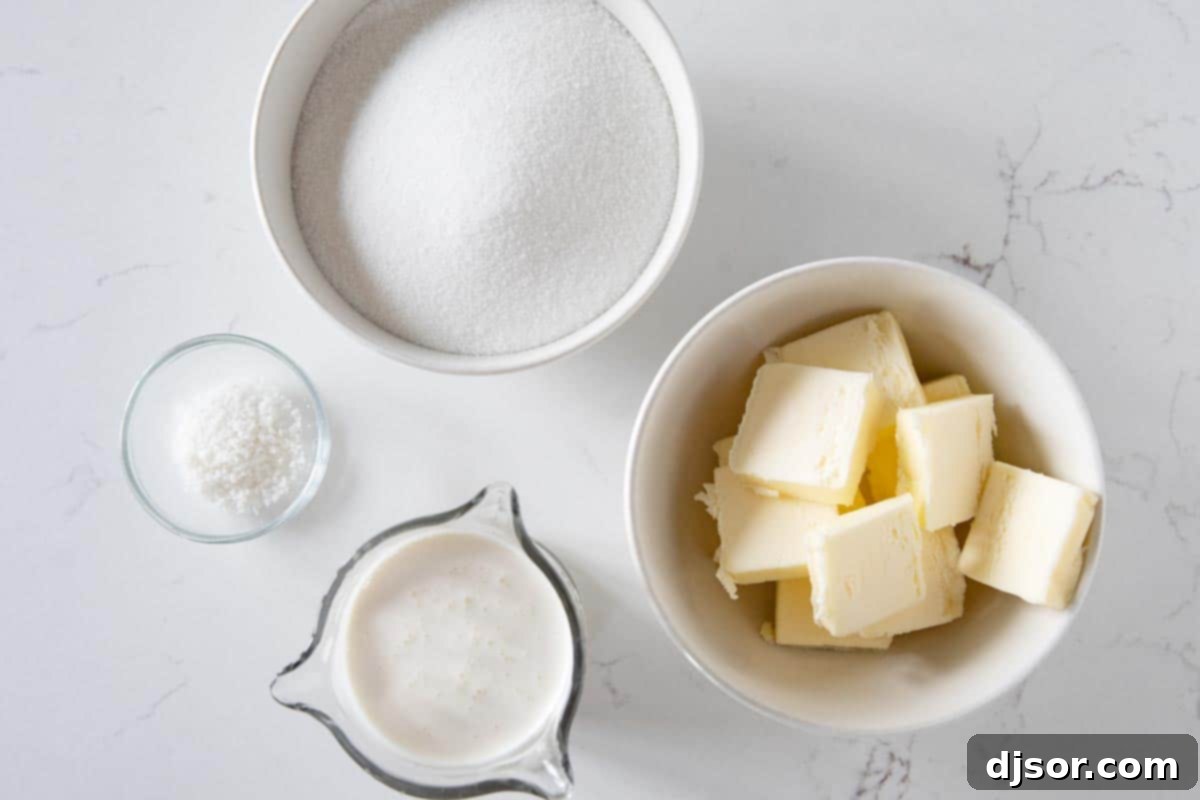 Essential ingredients for homemade salted caramel sauce: granulated sugar, butter, heavy cream, and flaky sea salt, laid out on a surface.