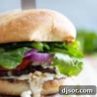 Ultimate Blue Cheese Burgers 2 Close up of a blue cheese burger, artfully presented with a steak knife through it, emphasizing its gourmet appeal.