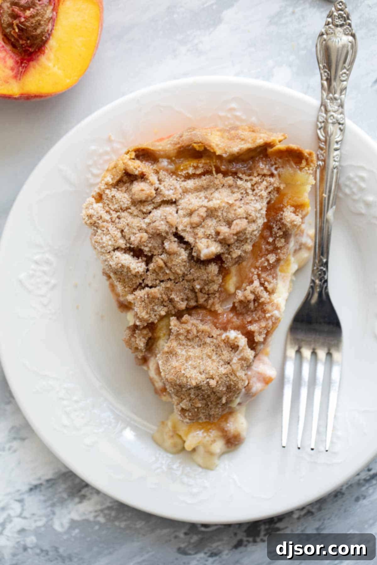Slice of sour cream peach pie on a plate with a fork.