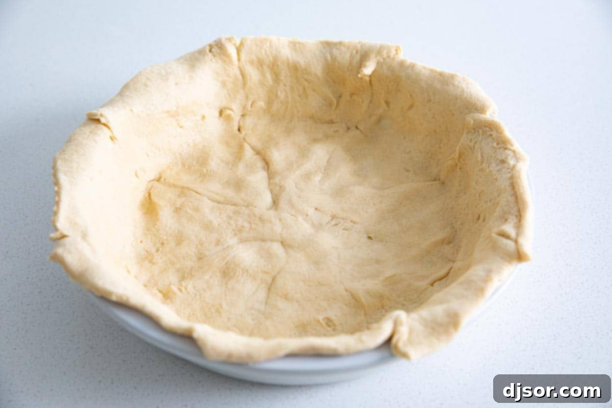 Preparing the Crescent Roll Crust for Taco Pie crescent roll dough laid out in a pie dish, forming the crust