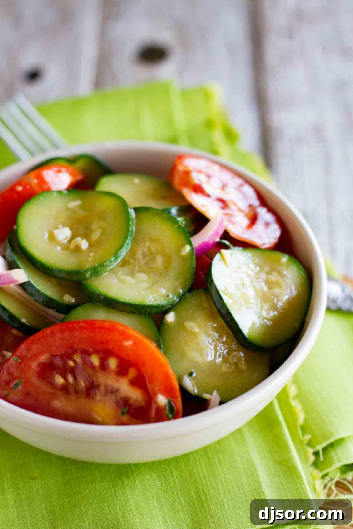 A vibrant bowl of fresh zucchini salad with juicy red tomatoes and thinly sliced red onions, ready to be served as a perfect summer side dish.