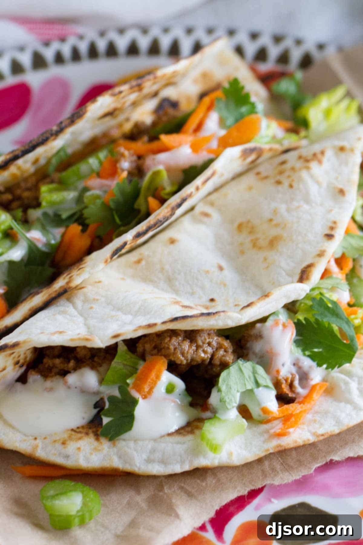 Two Buffalo Beef Tacos on a plate with blue cheese dressing and fresh cilantro.