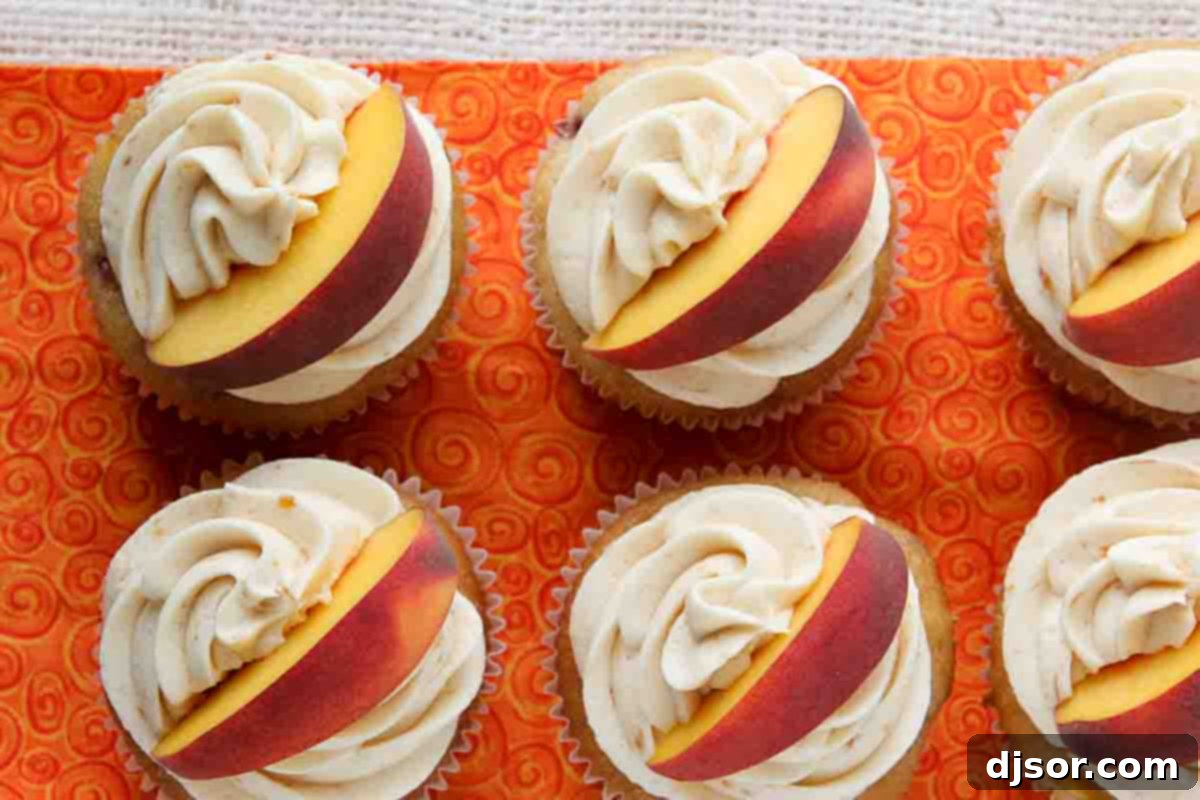 The best Peach Cupcakes - cupcakes are packed with peach flavor from peach jam and fresh peaches. Then they are topped with a delicious peach buttercream. Peach Cupcakes topped with peach buttercream and a fresh peach slice