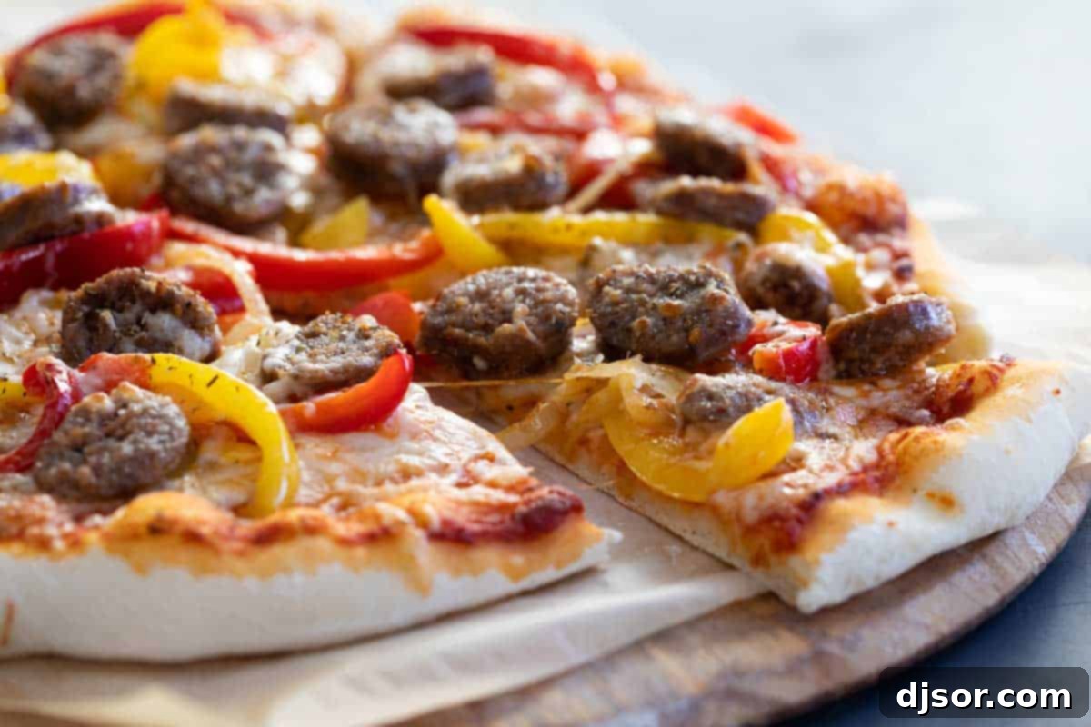 Homemade Italian Sausage and Peppers Pizza Close-up of a homemade Sausage and Peppers Pizza, showcasing Italian sausage, vibrant red and yellow bell peppers, and melted cheese.