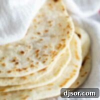 stack of homemade flour tortillas wrapped in a towel.