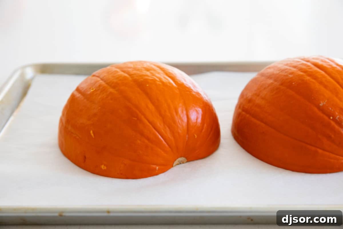 Pumpkin halves placed cut-side down on a parchment-lined baking sheet for roasting