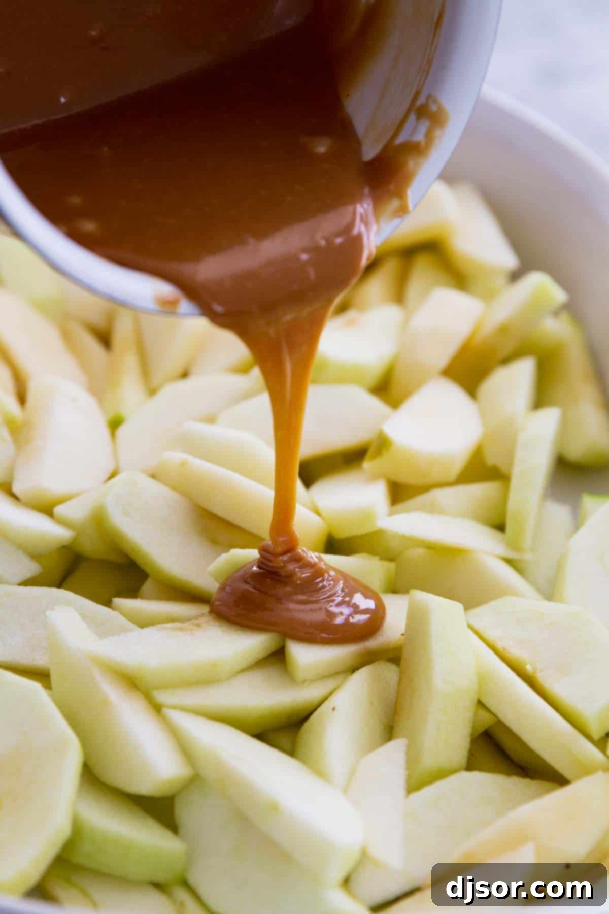 pouring caramel over apples in a baking dish.