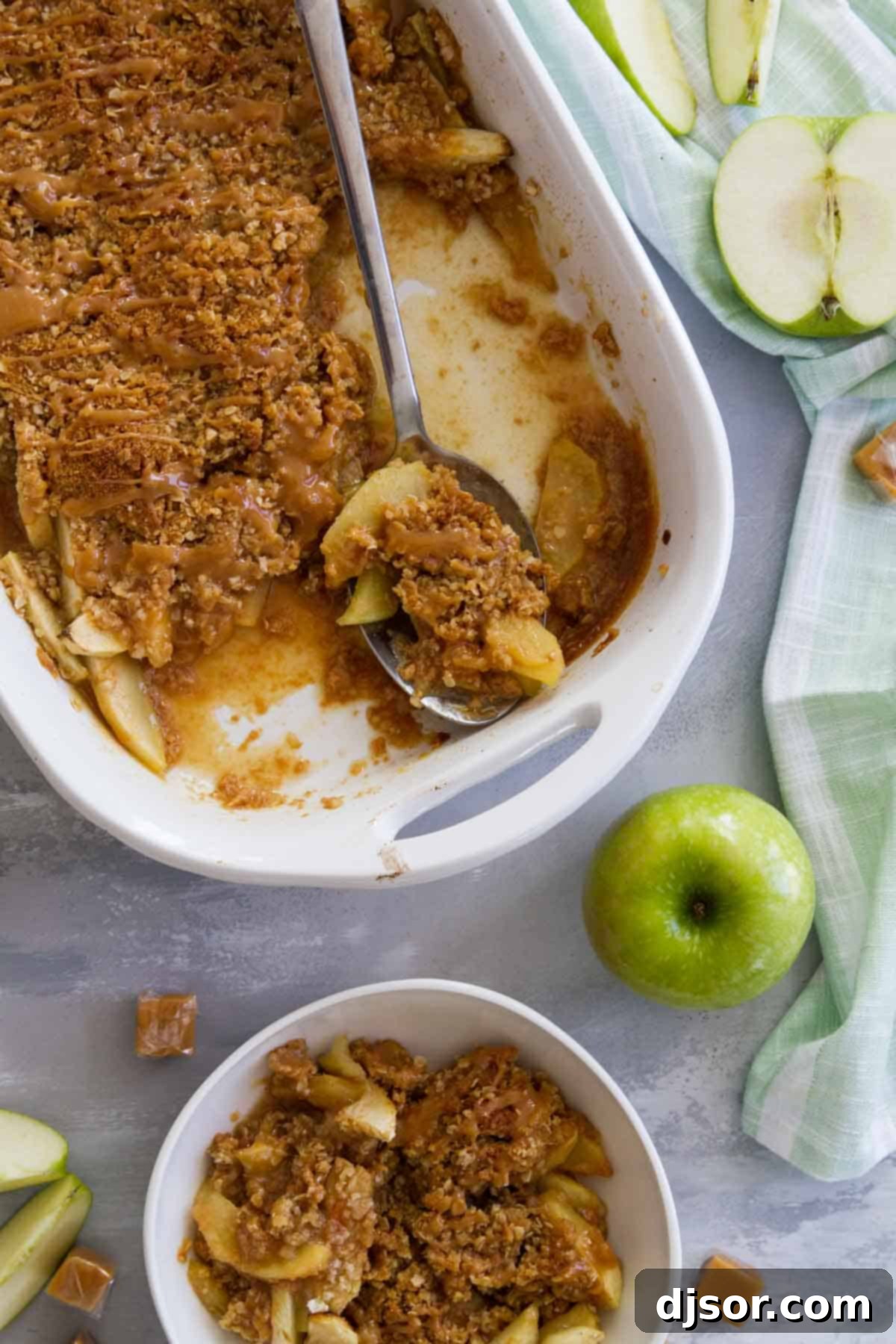 Baking dish of caramel apple crisp with a serving spoon.