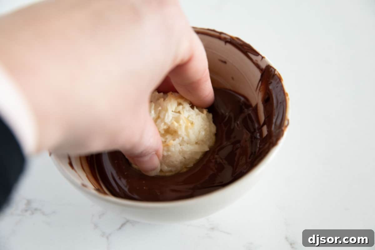 How to Dip Coconut Macaroons in Chocolate A perfectly golden coconut macaroon being dipped into a bowl of rich, melted chocolate, ready for an extra layer of decadence.