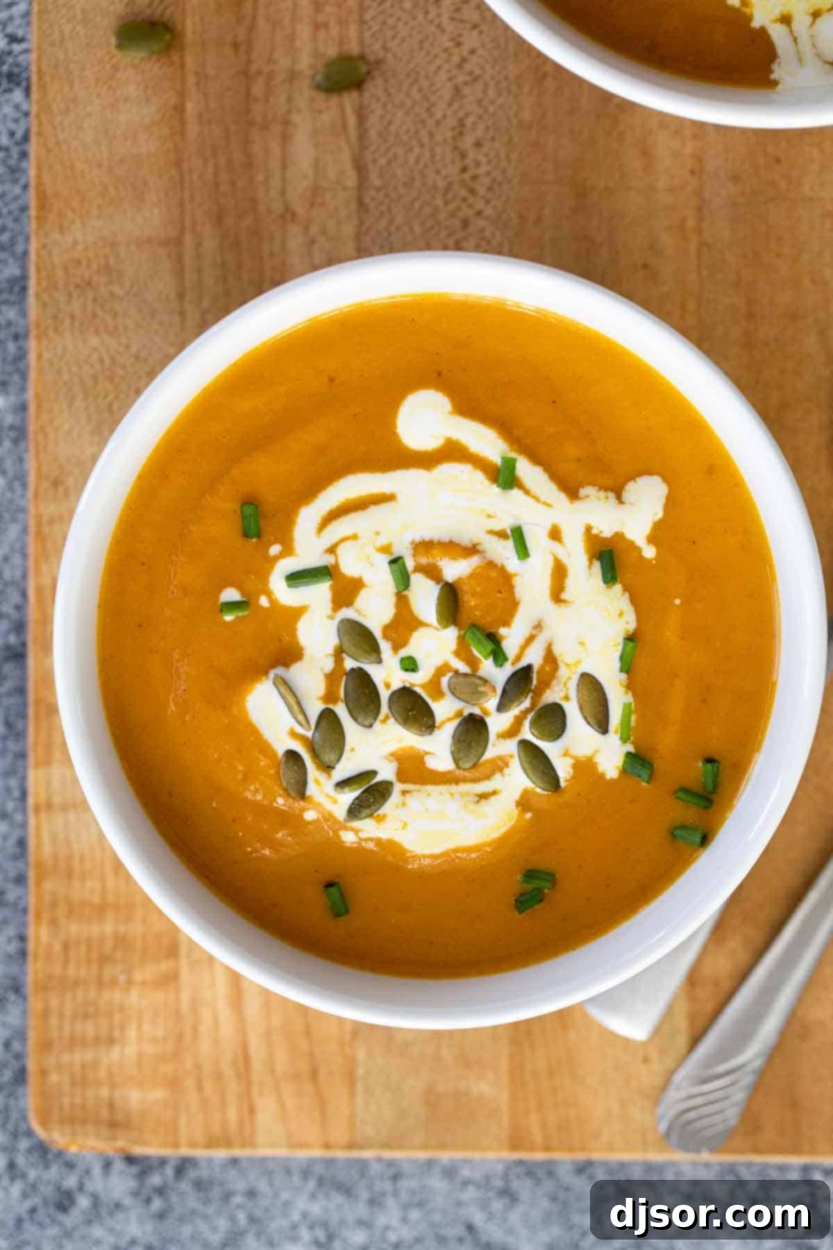 overhead view of a bowl of pumpkin soup on a cutting board